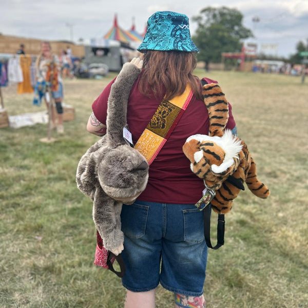 Person at festival with soft toy sloth and tiger backpacks